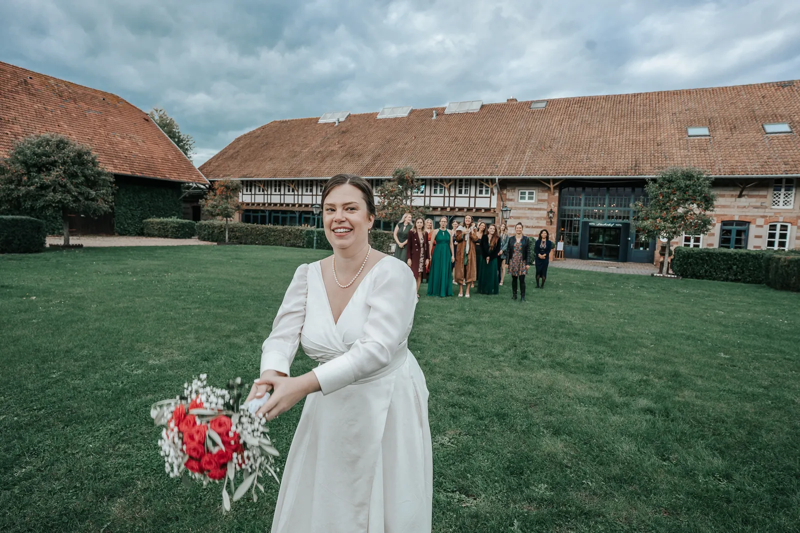 Brautstraußwurf von Hélène mit jubelnden Brautjungfern im Hintergrund – fotografiert by SB Snaps, Hochzeitsfotograf im Saarland