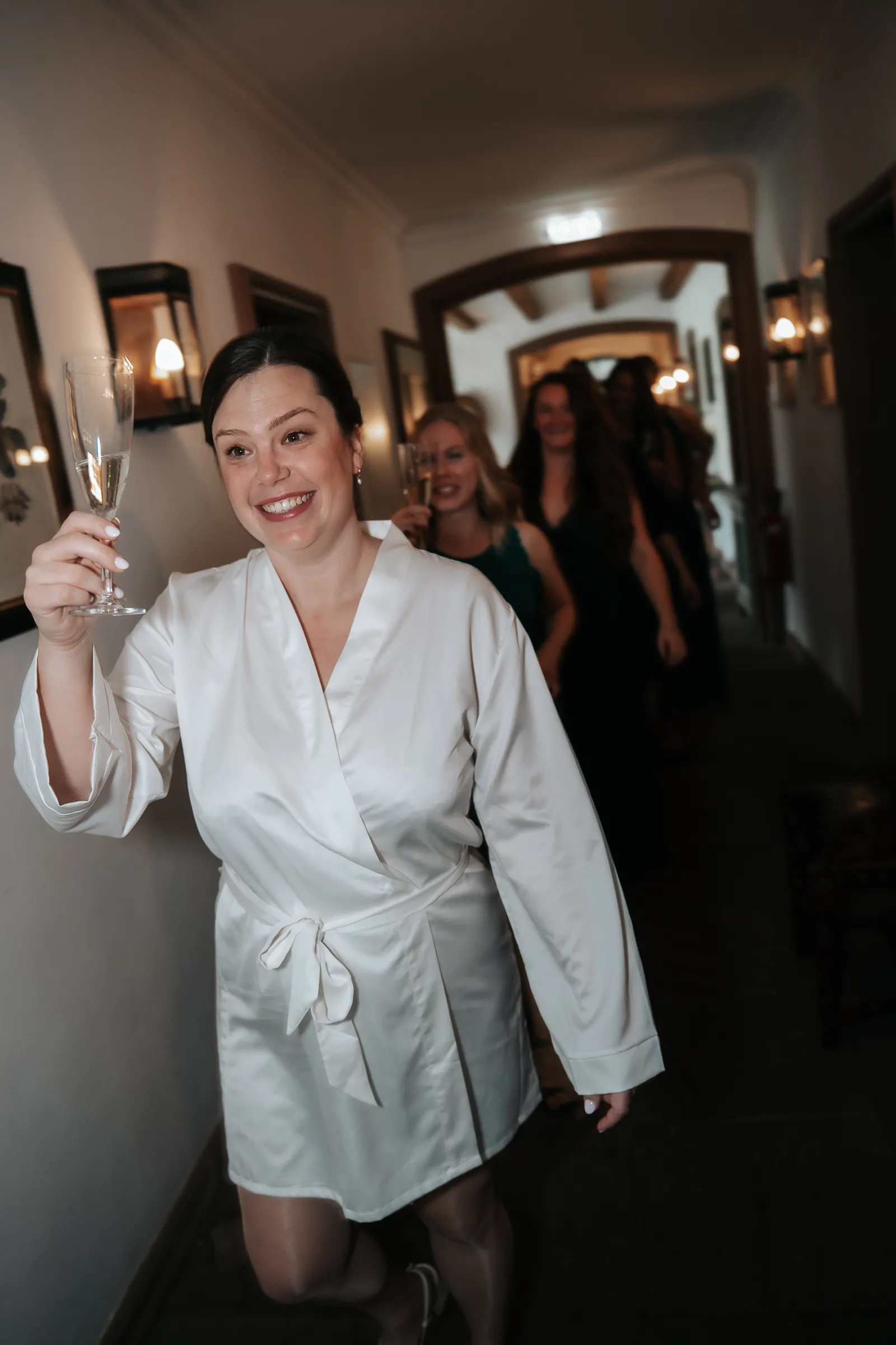 Hélène beim Get Ready mit einem Glas Sekt, begleitet von ihren Brautjungfern im Seidenmantel – fotografiert by SB Snaps, Hochzeitsfotograf im Saarland