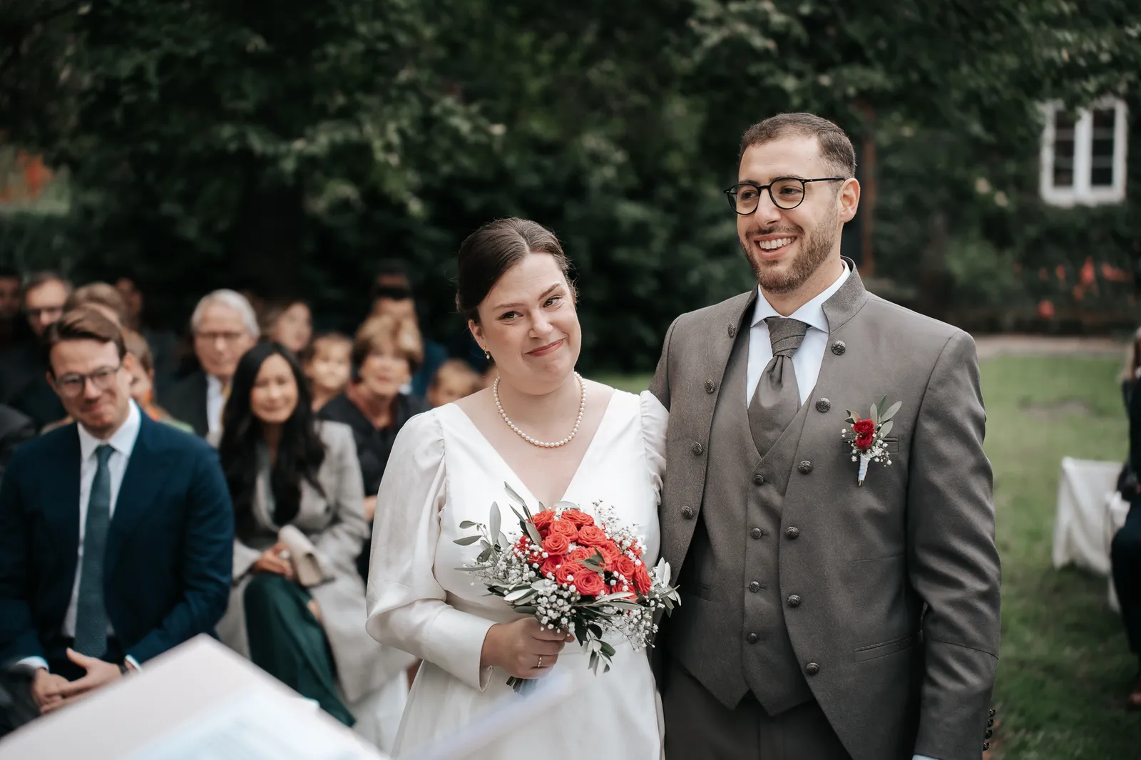 Hélène und Massimo hören lächelnd der Traurednerin am Trautisch zu – festgehalten by SB Snaps, Hochzeitsfotograf im Saarland